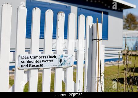 Fehmarn, Germania. 20 Apr 2021. Un segno con il detto 'la maledizione del camper, il cattivo tempo e i visitatori! P.S. Bad Weather Still Goes' è attaccato ad una recinzione di fronte ad una tenda su un campeggio. Credit: Frank Molter/dpa/Alamy Live News Foto Stock