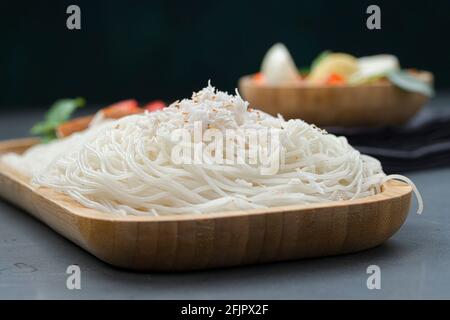 Ideyappam o noolappam, prodotto per la colazione dell'India del sud fatto usando riso crudo che è disposto in una base di servire di legno con uovo masala come buona combinazione Foto Stock