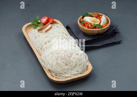 Ideyappam o noolappam, prodotto per la colazione dell'India del sud fatto usando riso crudo che è disposto in una base di servire di legno con uovo masala come buona combinazione Foto Stock