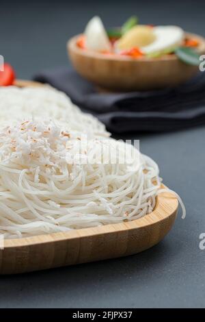 Ideyappam o noolappam, prodotto per la colazione dell'India del sud fatto usando riso crudo che è disposto in una base di servire di legno con uovo masala come buona combinazione Foto Stock