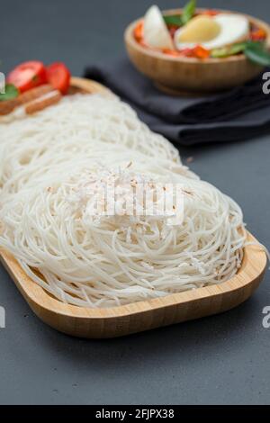 Ideyappam o noolappam, prodotto per la colazione dell'India del sud fatto usando riso crudo che è disposto in una base di servire di legno con uovo masala come buona combinazione Foto Stock