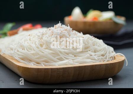 Ideyappam o noolappam, prodotto per la colazione dell'India del sud fatto usando riso crudo che è disposto in una base di servire di legno con uovo masala come buona combinazione Foto Stock