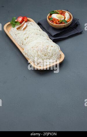 Ideyappam o noolappam, prodotto per la colazione dell'India del sud fatto usando riso crudo che è disposto in una base di servire di legno con uovo masala come buona combinazione Foto Stock