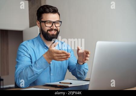 Imprenditore caucasico positivo che parla con la web camera del laptop Foto Stock