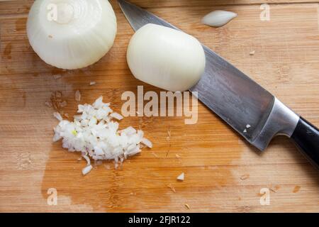 Mentre si preparano gli hamburger, le cipolle bianche vengono tritate con il coltello dello chef. Cipolle di messa a fuoco selettiva. Vista dall'alto. Foto Stock