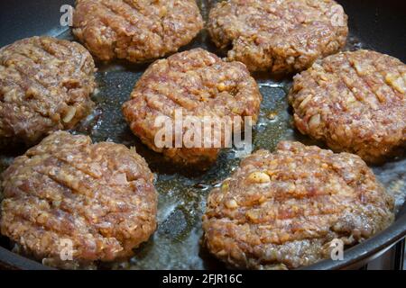 Sono necessari tre min. Le polpette di hamburger fatte in casa vengono cucinate in una padella di ghisa. Polpette Selective Focus Burger. Foto Stock