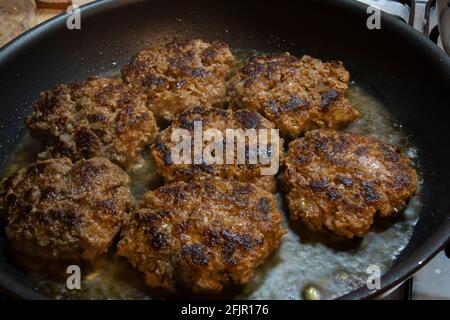 pronti a mangiare. polpette di hamburger fatte in casa sono cucinate in una padella di ghisa. Polpette Selective Focus Burger. Foto Stock