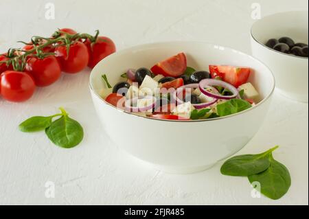 Insalata greca fresca e colorata o horiatiki con verdure servite con formaggio feta in ciotola bianca. Foto Stock