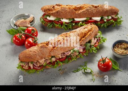 Da sopra yummy panini fatti di verdure con carne e. formaggio e posto vicino a pomodori biologici e spezie su grigio tabella Foto Stock