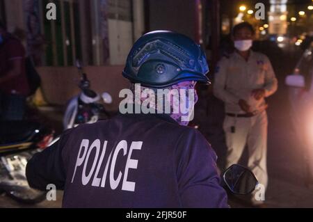 Durante un focolaio di COVID - 19, un poliziotto cambogiano in un camuffamento maschera protettiva viso / copertura si prepara a lasciare la scena di un'ambulanza raccogliendo una donna con coronavirus. 14 Marzo 2021. Stueng Meanchey, Phnom Penh, Cambogia. © Kraig Lieb Foto Stock