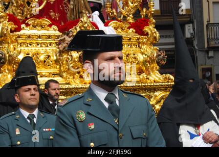 Siviglia, Spagna - settimana Santa, processione del Sabato Santo. Agenti della Guardia Civil e Nazareno con le tipiche cappe nere e l'abitudine. Foto Stock