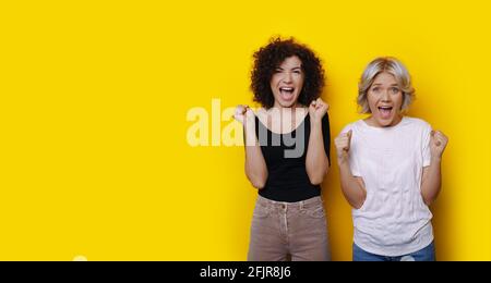 Gli amici dai capelli ricci sono scioccati da qualcosa che si pone su un parete gialla dello studio Foto Stock