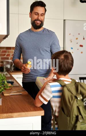 Padre che dà il suo figlio pranzo scatola con cibo sano Foto Stock