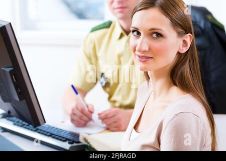 Funzionario di polizia nella stazione di polizia che lavora sul computer, la registrazione di un reclamo Foto Stock