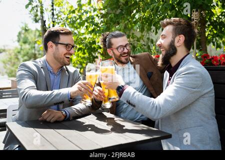 Concetto di pub per il tempo libero e l'amicizia. Amici maschi felici che bevono birra e bicchieri di clinciking al bar o al pub Foto Stock