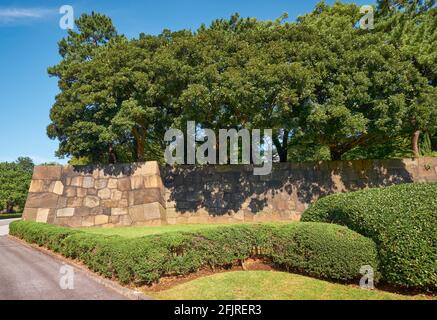 La vista della vecchia parete di pietra difensiva del castello di Edo circondato dagli alberi e dai cespugli formati nel giardino del Palazzo Imperiale di Tokyo. Tokyo. Giappone Foto Stock