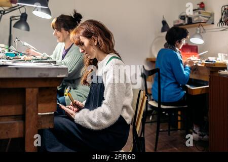 Foto di stock di donne focalizzate che lavorano in laboratorio di gioielleria. Foto Stock