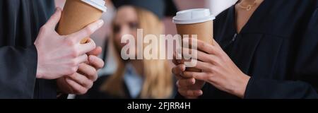 Vista ritagliata di laureati interrazziali che tengono il caffè per andare, banner Foto Stock