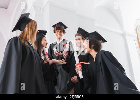 Allegri laureati interrazziali in caps con diplomi Foto Stock