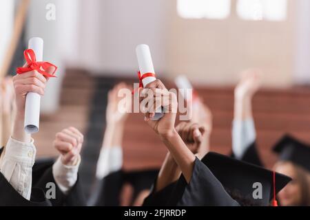 Vista ritagliata degli studenti interrazziali che detengono diplomi Foto Stock