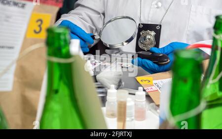 La polizia indaga con una lente d'ingrandimento impronte digitali su un coltello, immagine concettuale Foto Stock