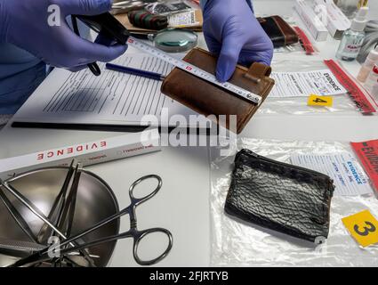 Ufficiale di polizia specializzato misura portafoglio in laboratorio di criminalità, immagine concettuale Foto Stock