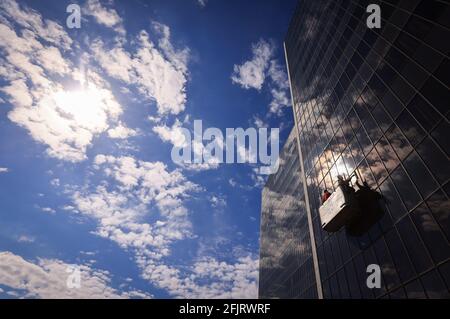 Amburgo, Germania. 26 Apr 2021. Due addetti alla pulizia in un ascensore puliscono le finestre della facciata dell'edificio Vattenfall in City Nord. Completato nel 1969, il complesso edilizio nel quartiere degli uffici City Nord di Amburgo è stato progettato dall'architetto e designer danese Arne Jacobsen. La griglia façade è composta da circa 6,500 riquadri. Credit: Christian Charisius/dpa/Alamy Live News Foto Stock