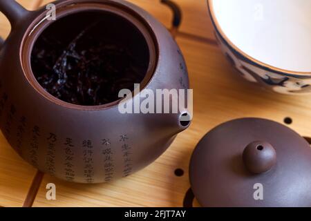 Teiera cinese di argilla yixing viola fatta a mano con pu pu erh e ciotola di porcellana su vassoio da tè di bambù o chaban. Cerimonia del tè, gong fu cha Foto Stock