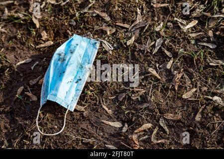 Foto della maschera medica di protezione usata a terra Foto Stock