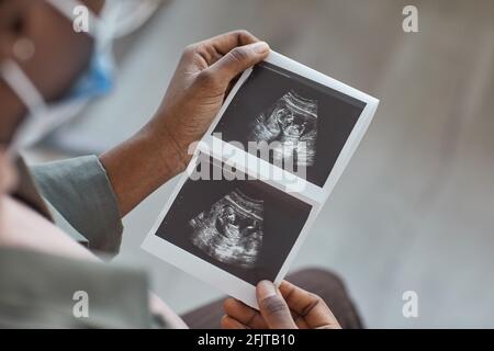 Primo piano di una donna che guarda l'immagine ecografica nelle sue mani durante la sua visita in ospedale Foto Stock