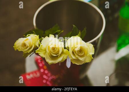 Tre belle rose gialle del giorno della mamma in vaso d'argento Foto Stock