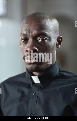 Ritratto del giovane sacerdote africano in colletto guardando la macchina fotografica Foto Stock