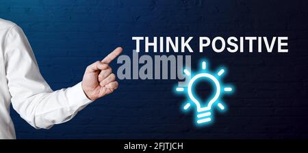 La mano dell'uomo d'affari punta alla parola pensa positivo con l'icona della lampadina. Pensiero positivo o positività per la creatività nel concetto di business. Foto Stock