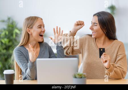 Due ragazze felici che fanno gli acquisti in linea. Ragazze che fanno shopping a casa. Foto Stock