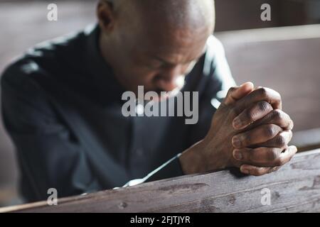 Uomo africano seduto con gli occhi chiusi e pregando nel chiesa Foto Stock
