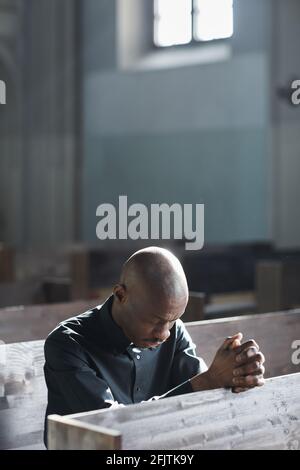 Uomo africano pregando mentre si siede nella chiesa Foto Stock