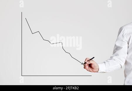 Mano di uomo d'affari disegna un grafico a linee in declino su sfondo grigio con spazio di copia. Foto Stock