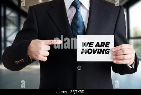 Uomo d'affari mostra una scheda con il messaggio che stiamo muovendo. Concetto di rilocazione aziendale o aziendale. Foto Stock