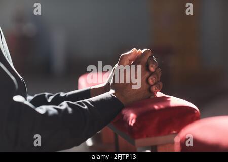 Primo piano dell'uomo africano che prega davanti all'altare nella chiesa Foto Stock