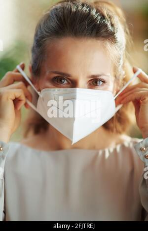 covid-19 pandemic. donna elegante in blusa grigia con maschera ffp2. Foto Stock