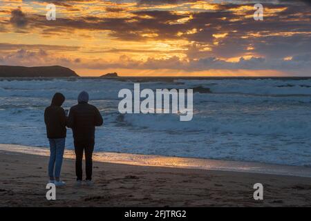 Persone che si trovano su Fistral Beach guardando uno spettacolare tramonto a Newquay in Cornovaglia. Foto Stock