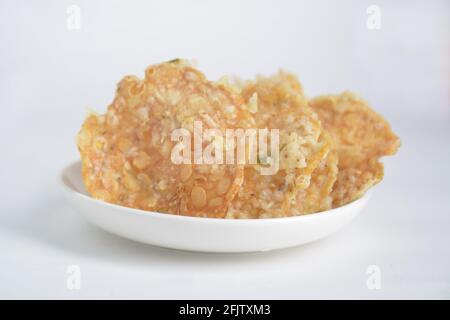 Keripik tempe , cracker tempeh in un piatto. Spuntino tradizionale indonesiano. Sfondo bianco Foto Stock