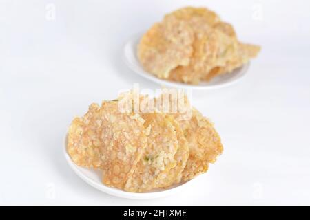 Keripik tempe , cracker tempeh in un piatto. Spuntino tradizionale indonesiano. Sfondo bianco Foto Stock