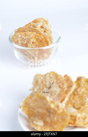 Keripik tempe , cracker tempeh in un piatto. Spuntino tradizionale indonesiano. Sfondo bianco Foto Stock