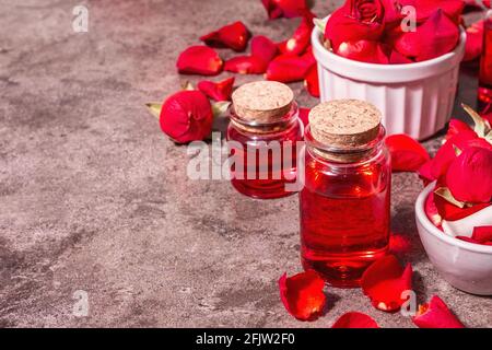 Rosewater con petali di rosa. Fare essenza di rosa organica per cucinare Kerala India. Aromaterapia, relax spa, concetto cosmetico. Luce moderna, Foto Stock