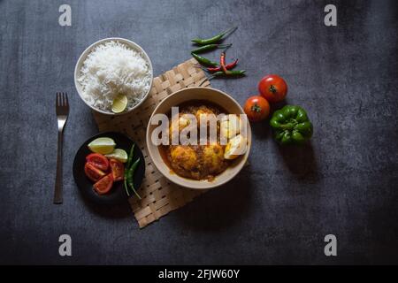 Popolare ingrediente indiano pranzo curry uovo in una ciotola insieme con riso e condimento insalata. Vista dall'alto, messa a fuoco selettiva. Foto Stock