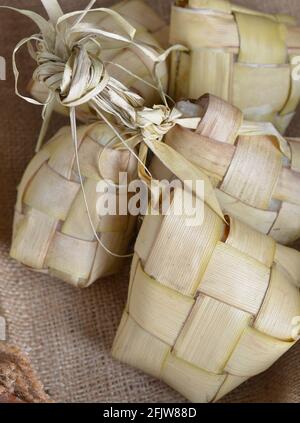 Ketupat, torta di riso in pochette a forma di diamante fatta da foglie di cocco intrecciate, cibo asiatico Foto Stock