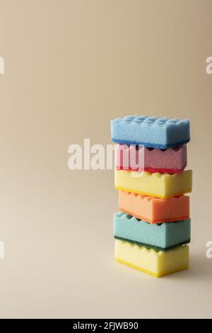 Pila di spugne per lavastoviglie multicolore su sfondo beige neutro, cucina casalinghi e concetto di pulizia Foto Stock