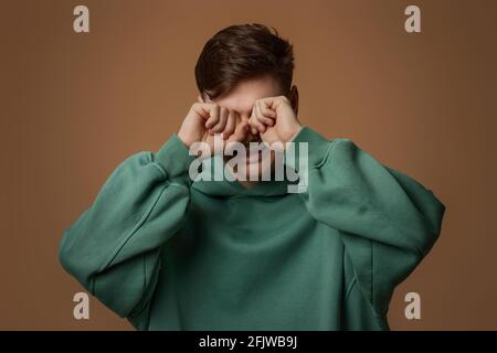 arrabbiato ragazzo piangendo in felpa verde Foto Stock
