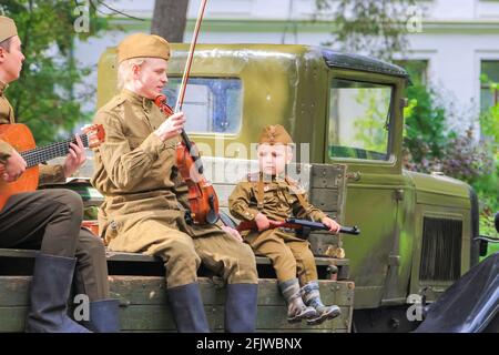 Ricostruzione dei tempi della Grande Guerra Patriottica. I soldati in macchina suonano il violino e la chitarra accanto al ragazzo. Mosca Russia Settembre 16 Foto Stock